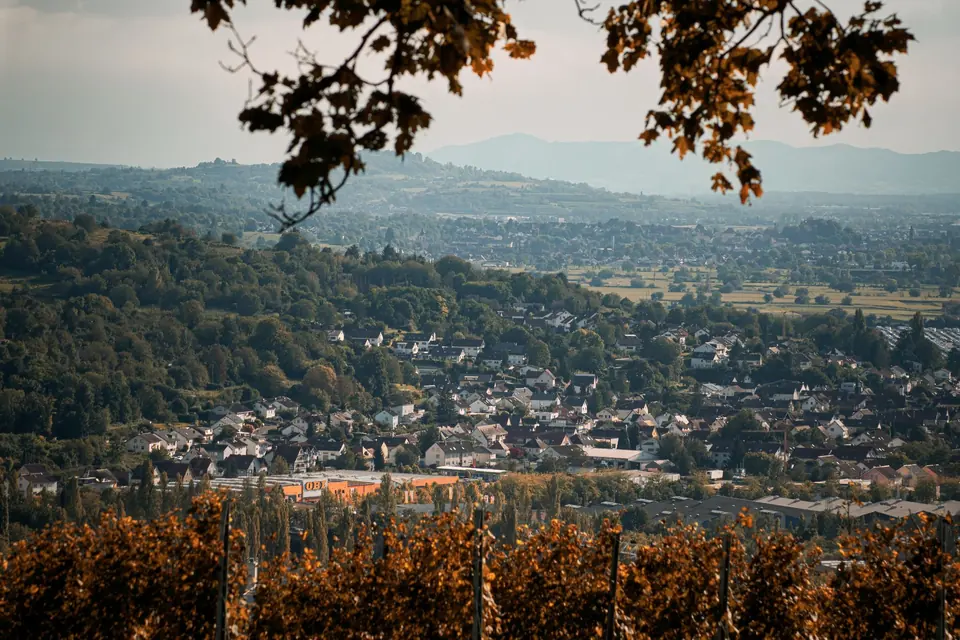 Malersches herbstliches Landschaftsbild mit Blick auf eine Stadt in Baden-Württemberg, umgeben von Hügeln.
